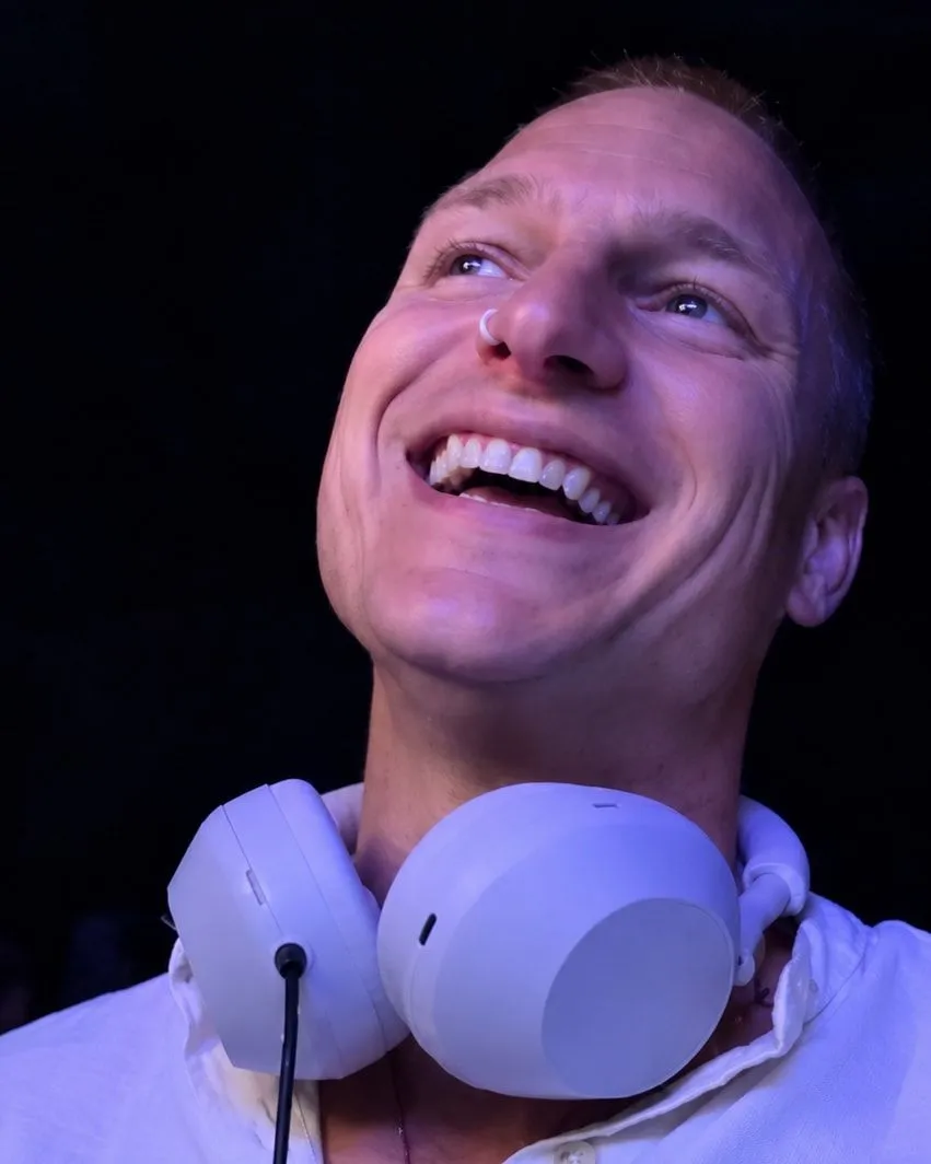 Ryan laughing, white headphones around his neck
